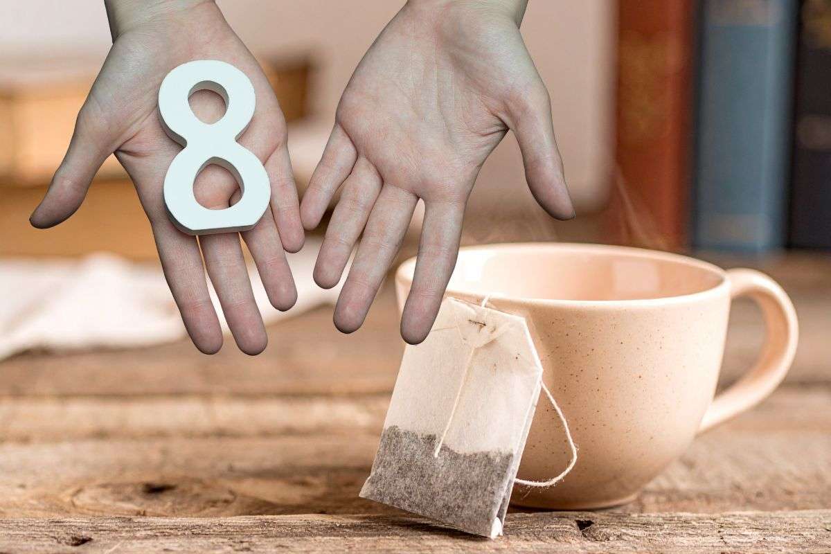 mani che mantengono numero 8 e bustine di tè