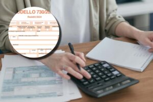 Una donna che calcola le tasse con una calcolatrice e, in evidenza, un fac-simile del modello 730