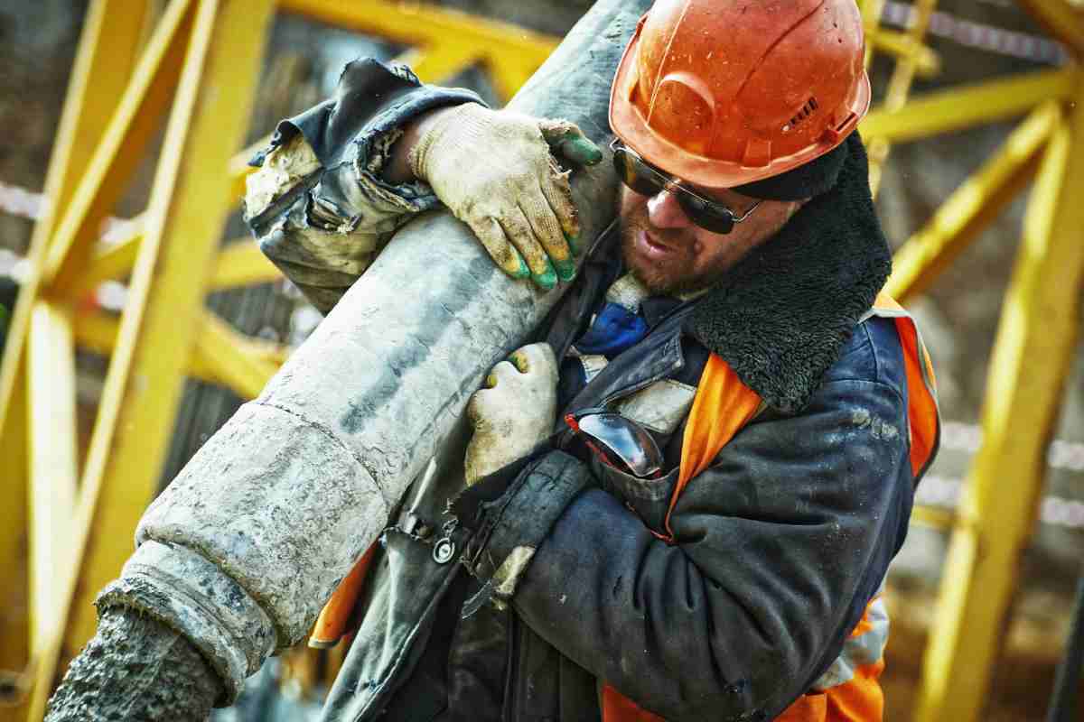 Un operaio con caschetto protettivo che trasporta un tubo