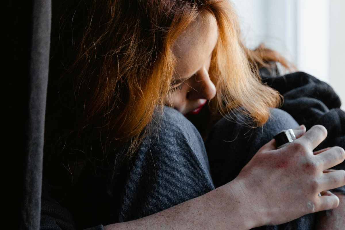 Una ragazza rannicchiata, con la testa sulle ginocchia