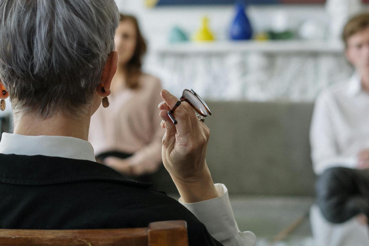 Uno psicologo di spalle e, sullo sfondo, una coppia di pazienti