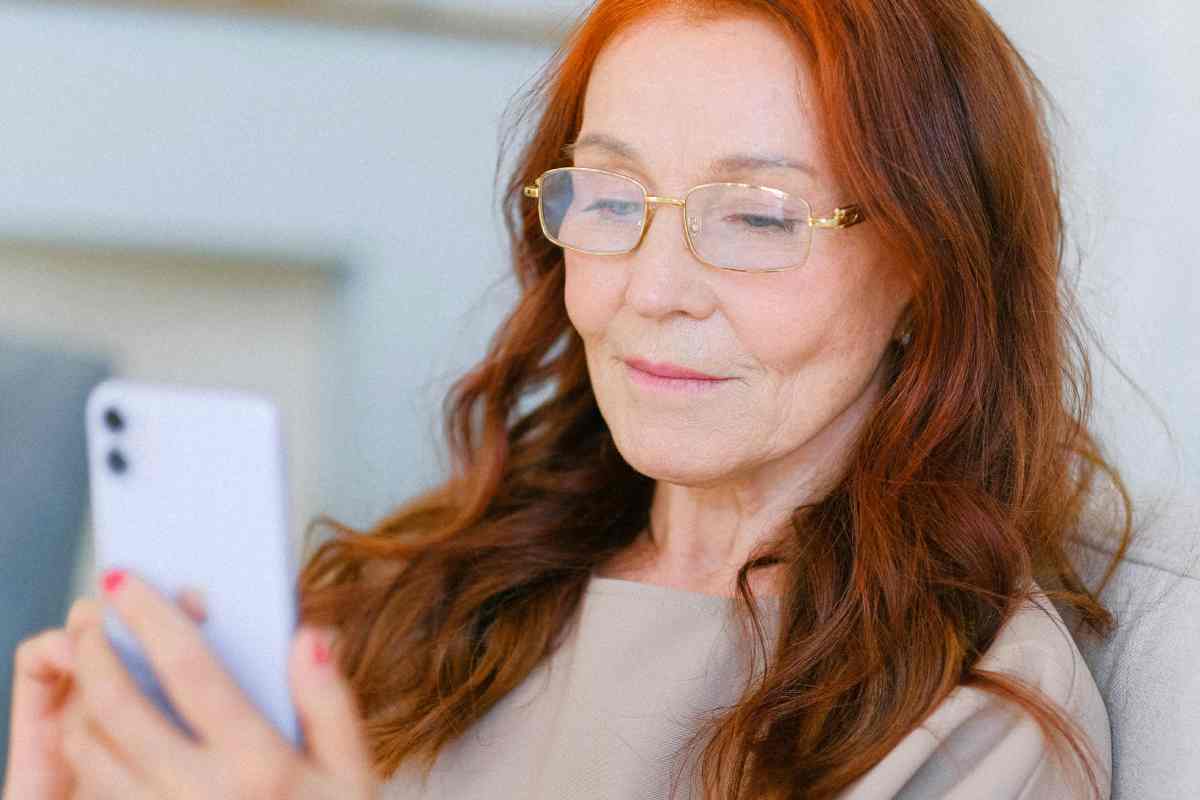 Una signora anziana con gli occhiali e guarda il telefonino